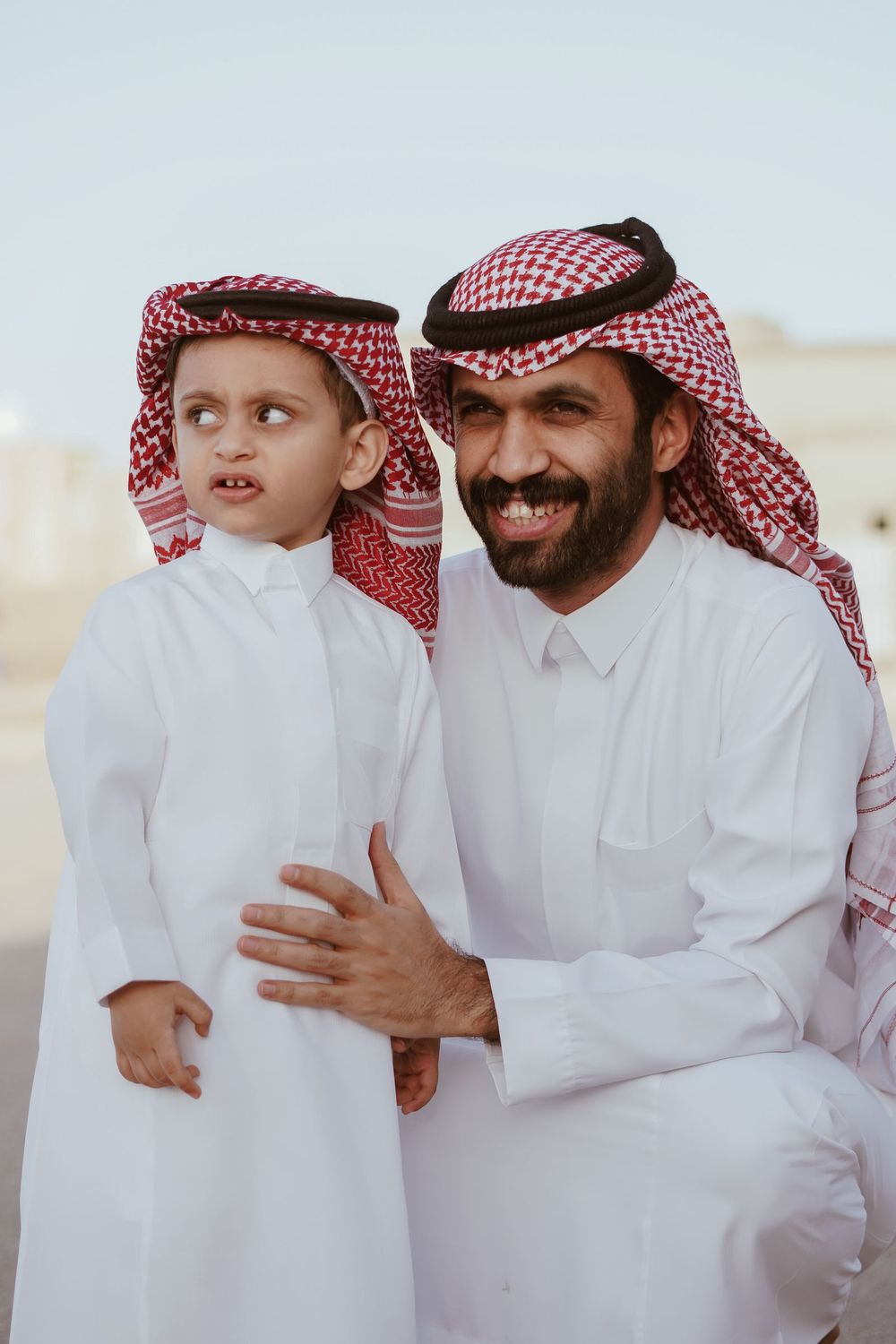 Smiling father with his son in traditional Saudi clothing